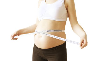 Hamile kadının destekleyici sorunsuz hamile sütyen ve boyut değişiklikleri çıplak karnı, mezura esnek cetvelle ölçme siyah yoga pantolon giyen kapatın. Beyaz arka plan, kopya alanı.