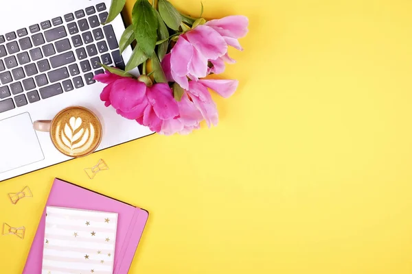 Feminine desktop, close up of laptop keyboard, blank clipboard, coffee, tulip flowers, eyewear. Flat lay composition, notebook computer, cappuccino cup, glasses eye wear, white background. Copy space.