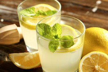 İki bardak buz dolu ferahlatıcı soğuk limonata İçecek taze nane w / güneş ışığında yaprakları kahverengi grunged ahşap masa, meyva suyu sıkacağı, olgun organik limon, bütün ve dilimlenmiş. Arka plan, kopya alanı, yakın çekim.