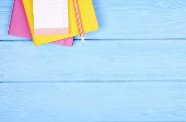 Boş kağıt levha ve kopya alanı metin onay kutusunu bir mavi ahşap Resepsiyon zemin üzerine üstten görünüm Not defteri, pembe ve sarı defter kapağı ve kalem. Kavram listesi yapmak için. Yakın, çok az düz lay.