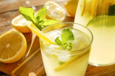 Limonata sürahi ve iki bardak soğuk buz, limon dilimleri, nane yaprakları ve kahverengi grunged ahşap masa, ülke tarafı yeşillik arka plan üzerinde payet ile narenciye içecek yenileniyor. Yakın çekim, alanı Kopyala.