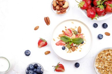 Yayınlama seçeneğini granola kase fındık, tahıl, meyve ve çilek, Yunan yoğurt karışımı ile. Sağlıklı vejetaryen kahvaltı, organik çilek, yaban mersini, nane, badem. Yakın çekim, görünümü, arka plan top.