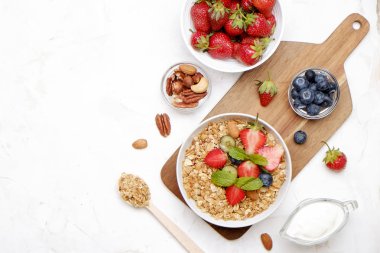 Yayınlama seçeneğini granola kase fındık, tahıl, meyve ve çilek, Yunan yoğurt karışımı ile. Sağlıklı vejetaryen kahvaltı, organik çilek, yaban mersini, nane, badem. Yakın çekim, görünümü, arka plan top.