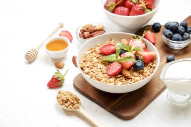 Yayınlama seçeneğini granola kase fındık, tahıl, meyve ve çilek, Yunan yoğurt karışımı ile. Sağlıklı vejetaryen kahvaltı, organik çilek, yaban mersini, nane, badem. Yakın çekim, görünümü, arka plan top.