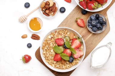 Yayınlama seçeneğini granola kase fındık, tahıl, meyve ve çilek, Yunan yoğurt karışımı ile. Sağlıklı vejetaryen kahvaltı, organik çilek, yaban mersini, nane, badem. Yakın çekim, görünümü, arka plan top.