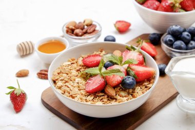 Yayınlama seçeneğini granola kase fındık, tahıl, meyve ve çilek, Yunan yoğurt karışımı ile. Sağlıklı vejetaryen kahvaltı, organik çilek, yaban mersini, nane, badem. Yakın çekim, görünümü, arka plan top.