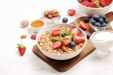 Yayınlama seçeneğini granola kase fındık, tahıl, meyve ve çilek, Yunan yoğurt karışımı ile. Sağlıklı vejetaryen kahvaltı, organik çilek, yaban mersini, nane, badem. Yakın çekim, görünümü, arka plan top.