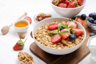 Yayınlama seçeneğini granola kase fındık, tahıl, meyve ve çilek, Yunan yoğurt karışımı ile. Sağlıklı vejetaryen kahvaltı, organik çilek, yaban mersini, nane, badem. Yakın çekim, görünümü, arka plan top.