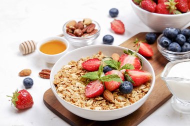 Yayınlama seçeneğini granola kase fındık, tahıl, meyve ve çilek, Yunan yoğurt karışımı ile. Sağlıklı vejetaryen kahvaltı, organik çilek, yaban mersini, nane, badem. Yakın çekim, görünümü, arka plan top.