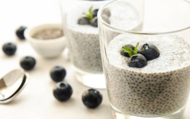 Chia muhallebi vegan badem sütü, yaban mersini ve tohumlar tarafında, ile iki porsiyon bardaklarda servis. Sağlıklı vejetaryen kahvaltı, çilek ve Yunan yoğurt, kaşık. Arka plan, kopya alanı, yakın çekim.