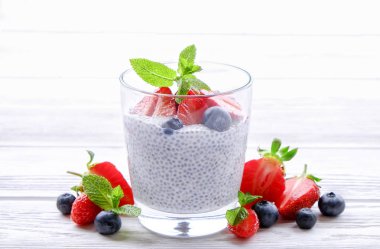 Vegan badem sütü, böğürtlen ve çilek, nane, chia puding bardakta servis bölümü. Sağlıklı vejetaryen kahvaltı, tohum, çilek, Yunan yoğurt, ahşap masa. Arka plan, yakın çekim, görünümü ana sayfa.