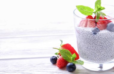 Vegan badem sütü, böğürtlen ve çilek, nane, chia puding bardakta servis bölümü. Sağlıklı vejetaryen kahvaltı, tohum, çilek, Yunan yoğurt, ahşap masa. Arka plan, yakın çekim, görünümü ana sayfa.