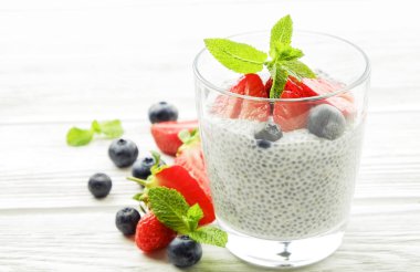 Vegan badem sütü, böğürtlen ve çilek, nane, chia puding bardakta servis bölümü. Sağlıklı vejetaryen kahvaltı, tohum çilek, Yunan yoğurt, ahşap masa. Arka plan, yakın çekim, alanı Kopyala