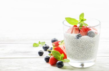 Vegan badem sütü, böğürtlen ve çilek, nane, chia puding bardakta servis bölümü. Sağlıklı vejetaryen kahvaltı, tohum çilek, Yunan yoğurt, ahşap masa. Arka plan, yakın çekim, alanı Kopyala