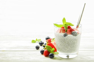 Vegan badem sütü, böğürtlen ve çilek, nane, chia puding bardakta servis bölümü. Sağlıklı vejetaryen kahvaltı, tohum çilek, Yunan yoğurt, ahşap masa. Arka plan, yakın çekim, alanı Kopyala