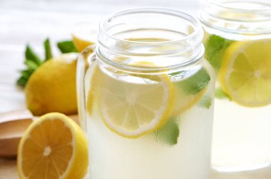 Ev yapımı ferahlatıcı limonata iki mason kavanoza bardak organik olgun limon, bütün ve yarıya, meyva suyu sıkacağı, karıştırma çubuğu, Sıkacağı rustik beyaz ahşap zemin üzerinde dilim. Yakın çekim, görünümü, kopya alanı top