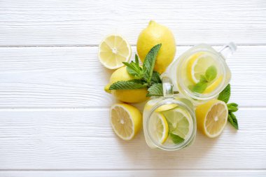 Ev yapımı ferahlatıcı limonata iki mason kavanoza bardak organik olgun limon, bütün ve yarıya, meyva suyu sıkacağı, karıştırma çubuğu, Sıkacağı rustik beyaz ahşap zemin üzerinde dilim. Yakın çekim, görünümü, kopya alanı top