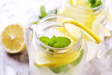 Ev yapımı ferahlatıcı limonata iki mason kavanoza bardak organik olgun limon, bütün ve yarıya, nane, Ice cube grunged gri beton tablo arka plan üzerinde dilim. Yakın çekim, görünümü, kopya alanı top.