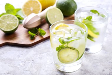 Serinletici alkolsüz mojito limonata içmek organik limon, limon dilimleri, iki kadeh yaprakları, saman, buz küpleri grunged gri beton tablo arka plan üzerine nane. Yakın çekim, görünümü, kopya alanı top.