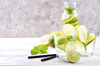 Vintage iki bardak serinletici alkolsüz mojito limonata içki şişesiyle dilimleri ile limon, limon, nane yaprakları, saman, buz üzerinde ahşap masa, beton arka plan. Yakın çekim, görünümü, kopya alanı top.