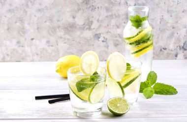 Vintage iki bardak serinletici alkolsüz mojito limonata içki şişesiyle dilimleri ile limon, limon, nane yaprakları, saman, buz üzerinde ahşap masa, beton arka plan. Yakın çekim, görünümü, kopya alanı top.