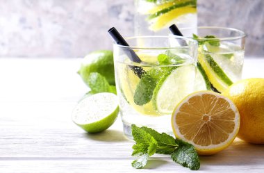 Vintage iki bardak serinletici alkolsüz mojito limonata içki şişesiyle dilimleri ile limon, limon, nane yaprakları, saman, buz üzerinde ahşap masa, beton arka plan. Yakın çekim, görünümü, kopya alanı top.