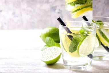 Vintage iki bardak serinletici alkolsüz mojito limonata içki şişesiyle dilimleri ile limon, limon, nane yaprakları, saman, buz üzerinde ahşap masa, beton arka plan. Yakın çekim, görünümü, kopya alanı top.