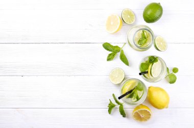 Vintage şişeyle serinletici alkolsüz mojito limonata, limon, limon dilimleri, içkiyle su pırıl pırıl iki bardak nane yaprakları, saman, ahşap masa arka plan. Yakın çekim, görünümü, kopya alanı top.