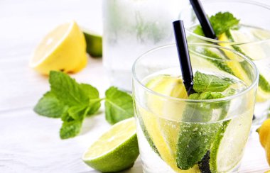 Vintage şişeyle serinletici alkolsüz mojito limonata, limon, limon dilimleri, içkiyle su pırıl pırıl iki bardak nane yaprakları, saman, ahşap masa arka plan. Yakın çekim, görünümü, kopya alanı top.
