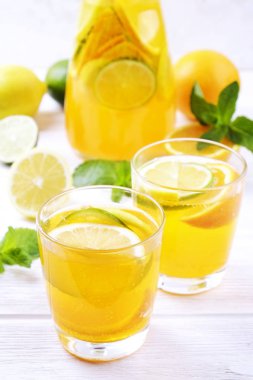 İki bardak ve ev yapımı ferahlatıcı limonata sürahi şişe organik olgun limon, portakal ve limon, nane ve rustik beyaz ahşap masa arka plan buza dilimleri ile. Yakın çekim, görünümü, kopya alanı top.