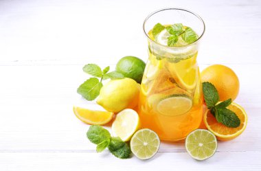 İki bardak ve ev yapımı ferahlatıcı limonata sürahi şişe organik olgun limon, portakal ve limon, nane ve rustik beyaz ahşap masa arka plan buza dilimleri ile. Yakın çekim, görünümü, kopya alanı top.