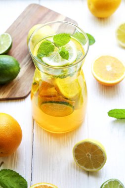 Buzlu limonata sürahi ve iki bardak, ahşap meyve sıkacağı, soğuk narenciye infüzyon su, limon ve limon, nane yaprakları, kesme tahtası üzerinde beyaz ahşap pencere. Daire pencere arka plan, yakın çekim, kopya alanı.