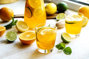 Buzlu limonata sürahi ve iki bardak, ahşap meyve sıkacağı, soğuk narenciye infüzyon su, limon ve limon, nane yaprakları, kesme tahtası üzerinde beyaz ahşap pencere. Daire pencere arka plan, yakın çekim, kopya alanı.