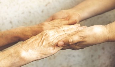 Yaşlı olgun kadın bakım tesisi hastane personel hemşire yardım alır. Üst düzey kadın w / yaşlı kırışık cilt ve bakım verici ellerini kapatın. Büyük anne günlük yaşam. Arka plan, kopya alanı.