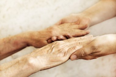 Yaşlı olgun kadın bakım tesisi hastane personel hemşire yardım alır. Üst düzey kadın w / yaşlı kırışık cilt ve bakım verici ellerini kapatın. Büyük anne günlük yaşam. Arka plan, kopya alanı.