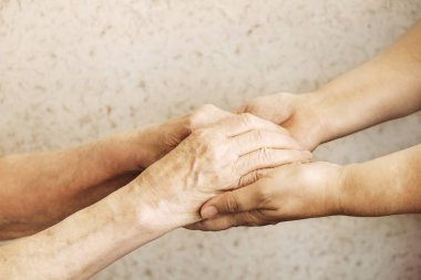 Yaşlı olgun kadın bakım tesisi hastane personel hemşire yardım alır. Üst düzey kadın w / yaşlı kırışık cilt ve bakım verici ellerini kapatın. Büyük anne günlük yaşam. Arka plan, kopya alanı.