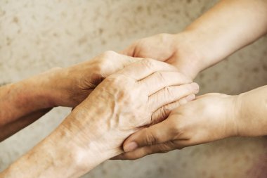 Yaşlı olgun kadın bakım tesisi hastane personel hemşire yardım alır. Üst düzey kadın w / yaşlı kırışık cilt ve bakım verici ellerini kapatın. Büyük anne günlük yaşam. Arka plan, kopya alanı.