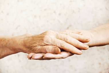 Yaşlı olgun kadın bakım tesisi hastane personel hemşire yardım alır. Üst düzey kadın w / yaşlı kırışık cilt ve bakım verici ellerini kapatın. Büyük anne günlük yaşam. Arka plan, kopya alanı.