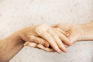 Yaşlı olgun kadın bakım tesisi hastane personel hemşire yardım alır. Üst düzey kadın w / yaşlı kırışık cilt ve bakım verici ellerini kapatın. Büyük anne günlük yaşam. Arka plan, kopya alanı.