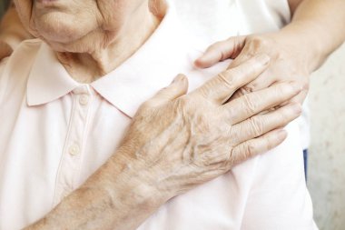 Yaşlı bakım evindeki olgun bir kadın hastane personeli hemşiresinden yardım alıyor. Yaşlı bir kadın, yaşlı, buruşuk bir cilt ve bakım yapan birinin elleri. Her gün anneanne. Arkaplan, kopyala boşluk, kapat