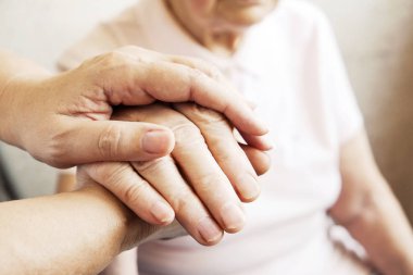 Yaşlı olgun kadın bakım tesisi hastane personel hemşire yardım alır. Üst düzey kadın w / yaşlı kırışık cilt ve bakım verici ellerini kapatın. Büyük anne günlük yaşam. Arka plan, kopya alanı.