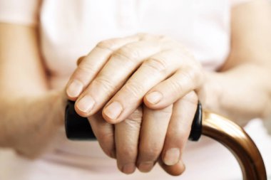 Yaşlı kadın bakım evinde, dört kamışı yürüyüş tutarak açıkça görünür damarlar ile el buruşuk. Yaşlılık üst düzey Bayan silah çiller ile yardım sopa kolu bar üzerinde yatıyordu. Arka plan, yakın çekim, alanı Kopyala.