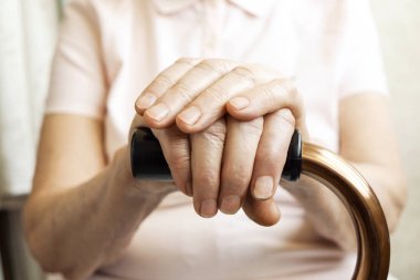 Yaşlı kadın bakım evinde, dört kamışı yürüyüş tutarak açıkça görünür damarlar ile el buruşuk. Yaşlılık üst düzey Bayan silah çiller ile yardım sopa kolu bar üzerinde yatıyordu. Arka plan, yakın çekim, alanı Kopyala.