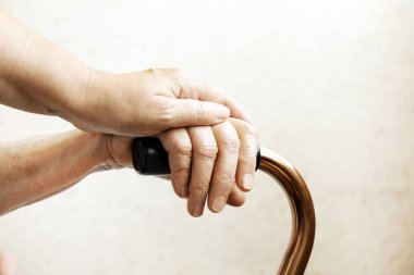 ' Yaşlı çift baston sapı tutan üst düzey kadın fecility iyi bak. Hastane bakım evinde, baston ile oturma rahatlatıcı olgun erkek hemşire. Arka plan, w / kırışık cilt eller üzerinde Kapat.