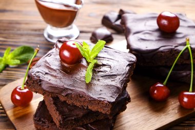 Ev yapımı kek kare parçaları, Yapıştır, kiraz ve pekan fındık ahşap masa üzerinde koyu çikolata yayıldı. Yüksek kalorili pasta. Kakao tatlılar, şekil için kötü dayalı. Yakın çekim, uzay arka plan, üstten görünüm Kopyala.