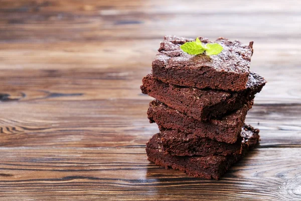 Yığın kare koyu çikolata yayıldı Yapıştır ahşap doku tablo ile ev yapımı kek parçaları. Yüksek kalorili pasta. Kakao tatlılar, şekil için kötü dayalı. Yakın, arka plan, top görünümü, kopya alanı.