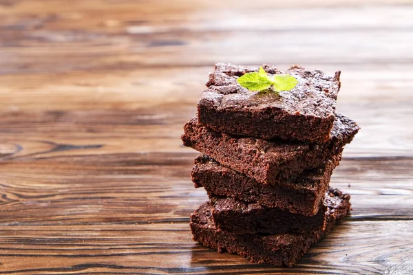 Yığın kare koyu çikolata yayıldı Yapıştır ahşap doku tablo ile ev yapımı kek parçaları. Yüksek kalorili pasta. Kakao tatlılar, şekil için kötü dayalı. Yakın, arka plan, top görünümü, kopya alanı.