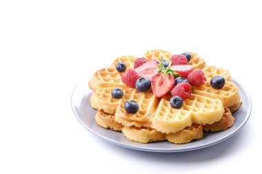 Çeşitli çilek karışımı, çilek, böğürtlen, ahududu ile kalp şekli Belçika Waffle ve nane yaprağı beyaz seramik plaka üzerinde kırmızı kuş üzümü süslenmiş. Yakın çekim, kopya alanı, arka plan, üstten görünüm.