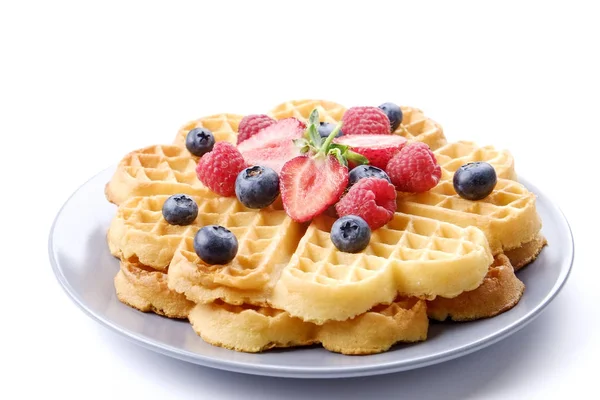 Çeşitli çilek karışımı, çilek, böğürtlen, ahududu ile kalp şekli Belçika Waffle ve nane yaprağı beyaz seramik plaka üzerinde kırmızı kuş üzümü süslenmiş. Yakın çekim, kopya alanı, arka plan, üstten görünüm.