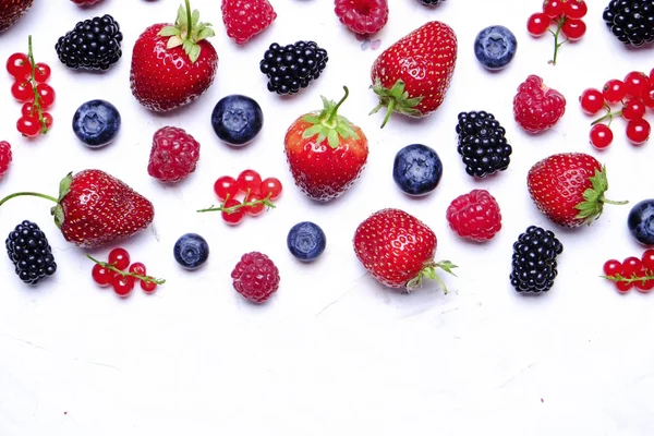 Hasat yığın beyaz zemin üzerine karışık meyveli demet. Taze organik çilek, yaban mersini, böğürtlen ve somun ile renkli kompozisyon. Temiz kavramı yeme. Yakın çekim, uzay, üstten görünüm Kopyala